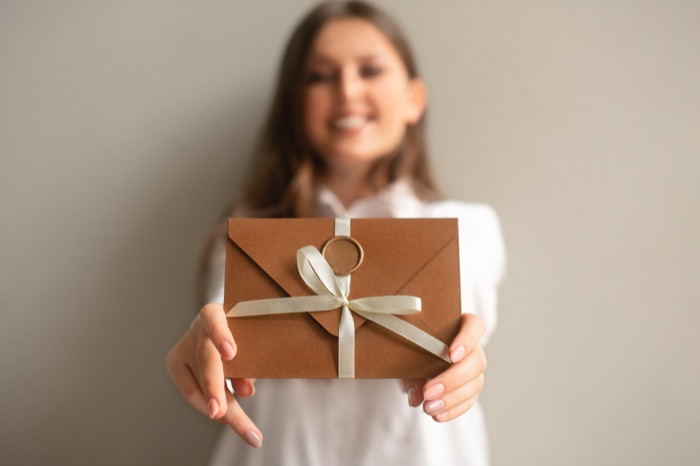 Femme tenant un bon cadeau emballé avec un ruban